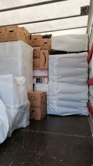 Intérieur du camion chargé : matelas filmés, cartons calés et arrimés
