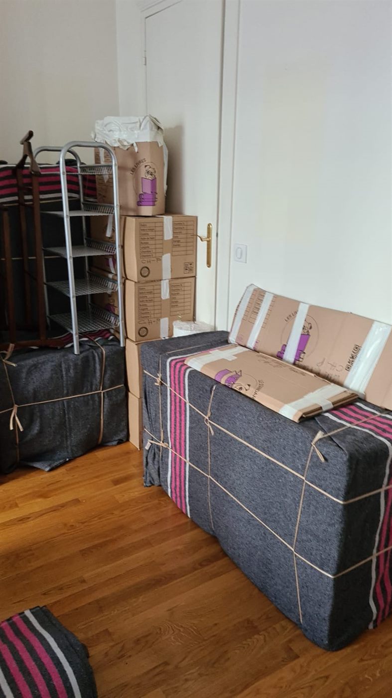Meubles emballés et cartons étiquetés rangés le long d'un mur, prêts pour le chargement